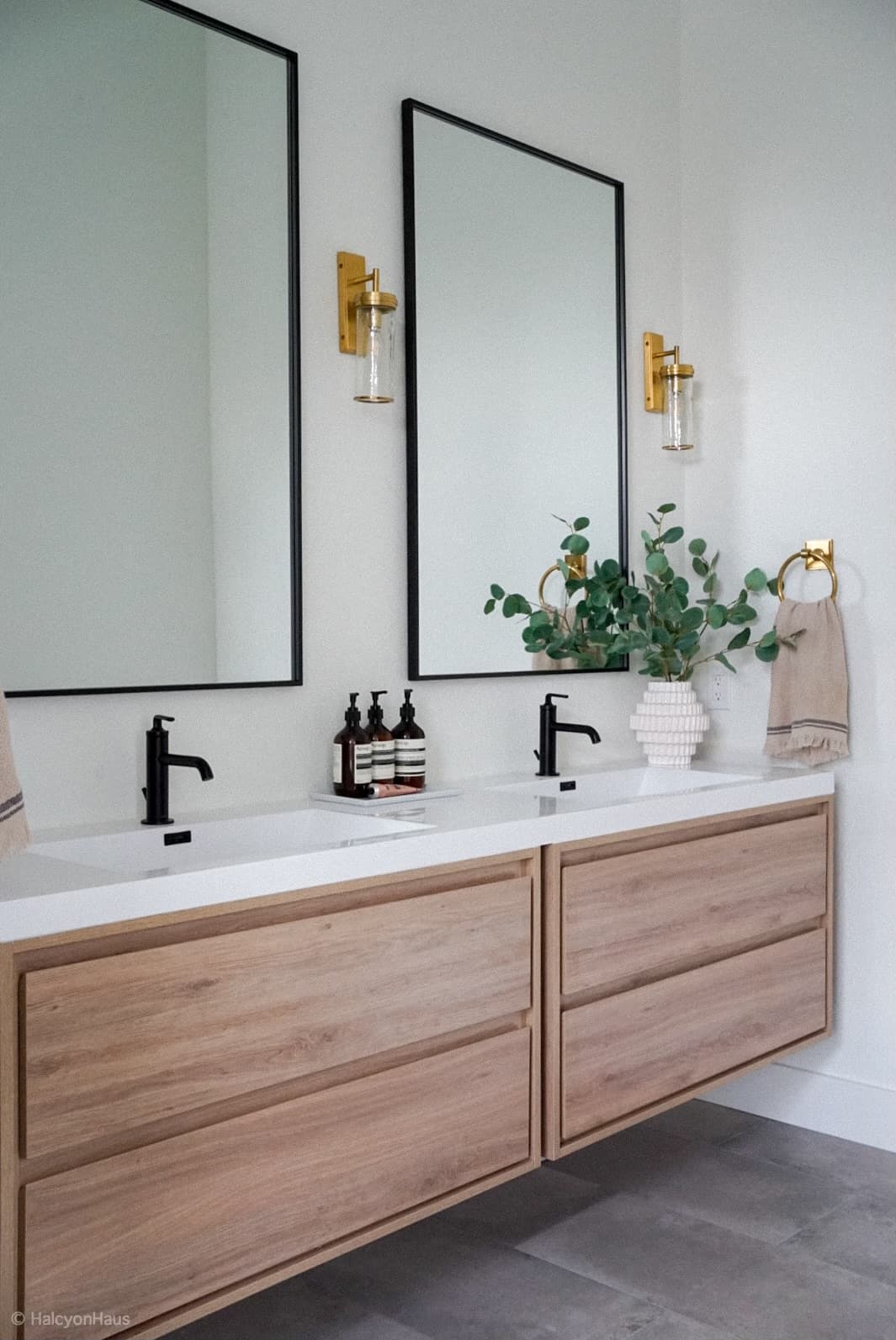 Floating wood double vanity with black faucets, black framed mirrors, and brass sconces in a Highlands Ranch bathroom