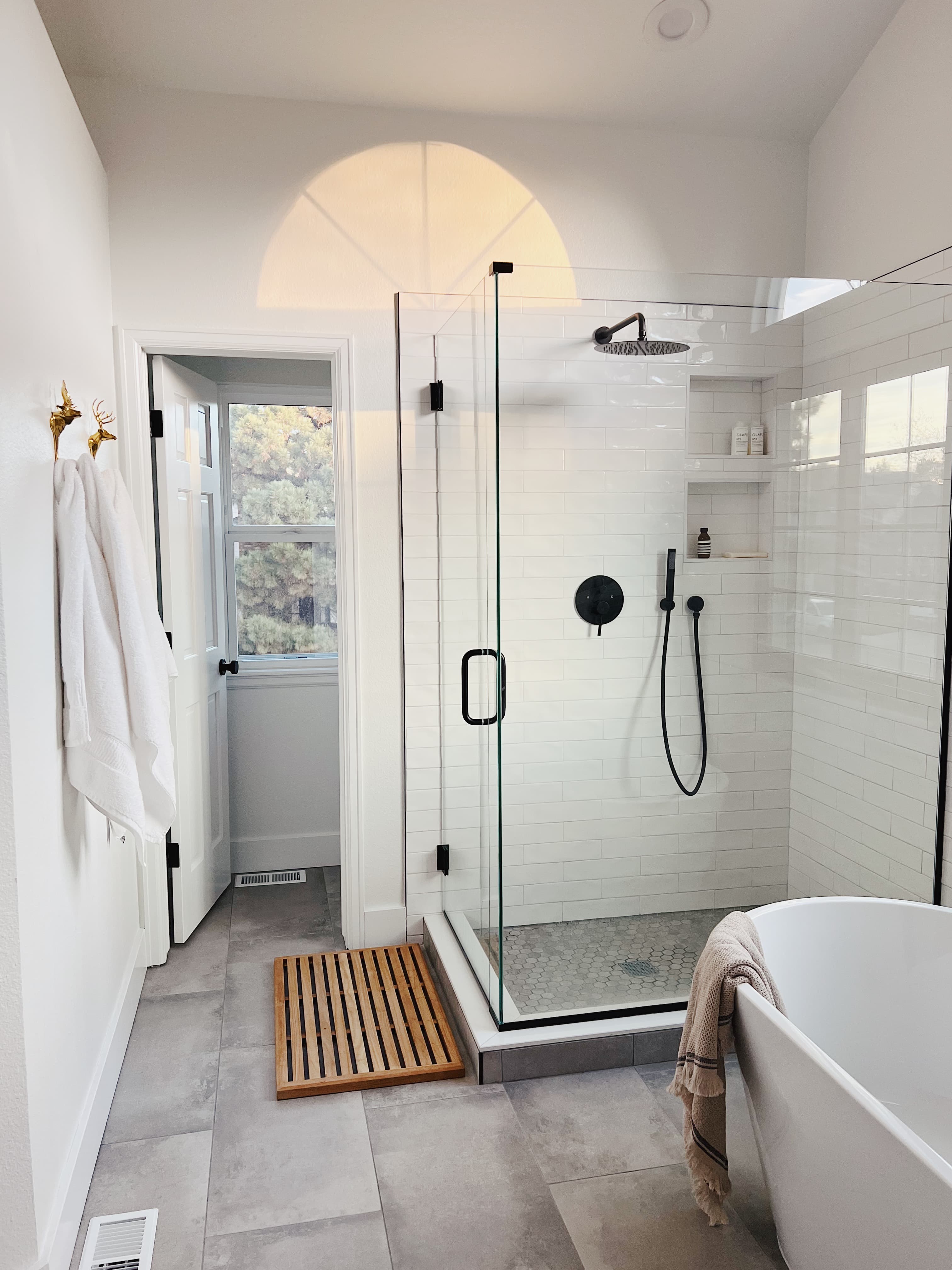 Highlands Ranch bathroom with a glass walk-in shower, white tile, a freestanding tub, and an arched window