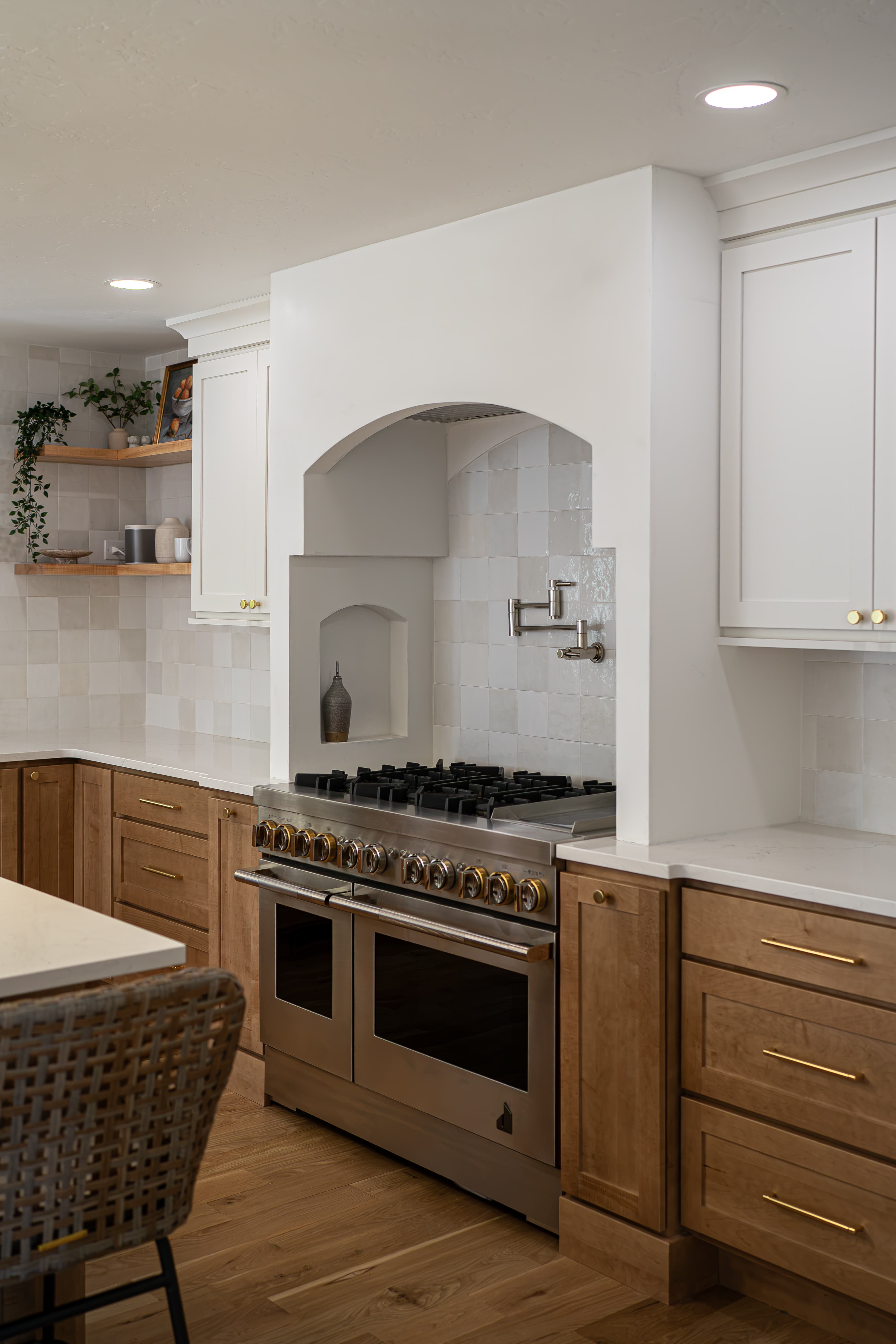 Custom arched range hood with a spice niche and pot filler above a double-oven range in a Greenwood Village kitchen