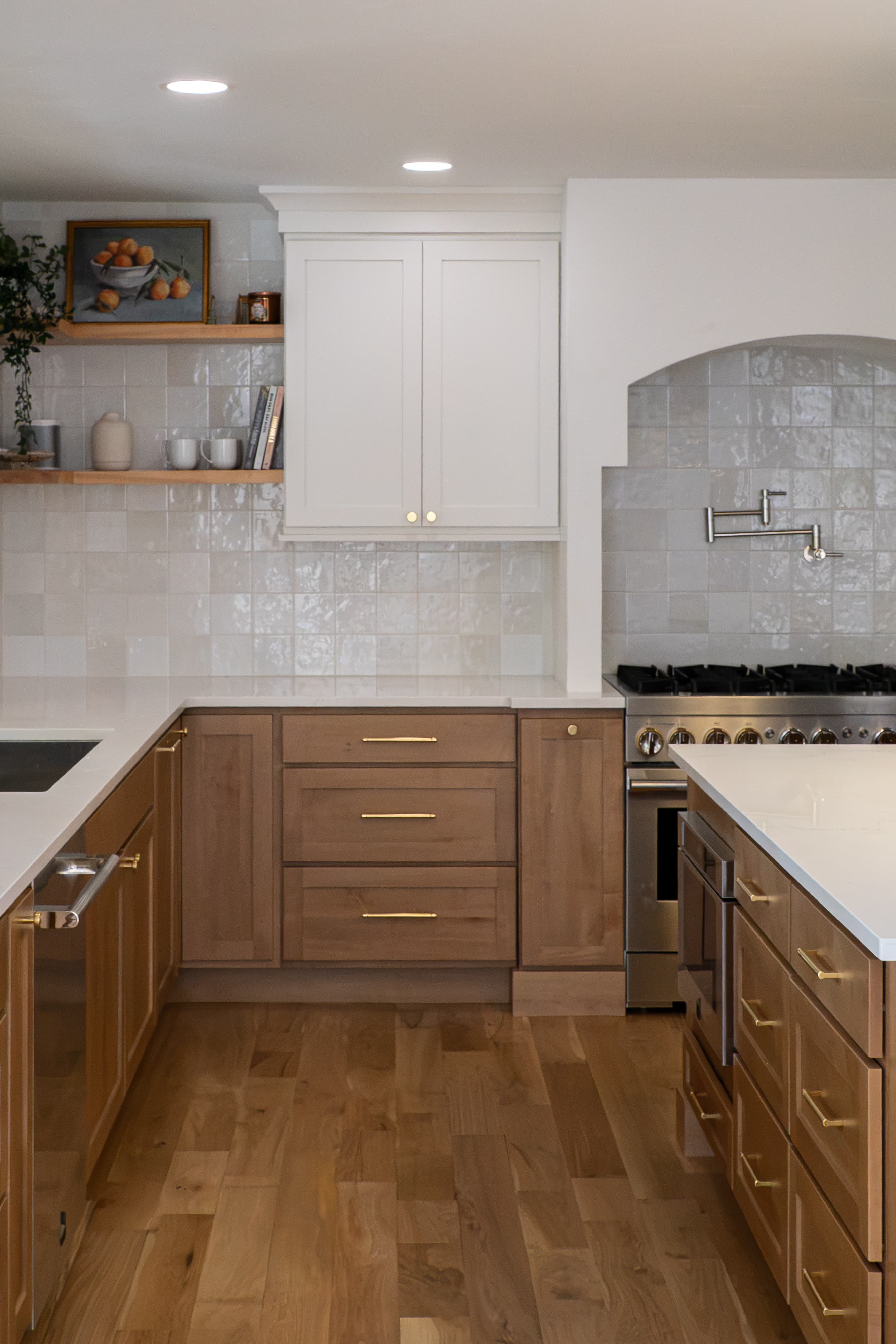 Honey maple drawers with lacquered brass pulls beneath soft white uppers and open wood shelving