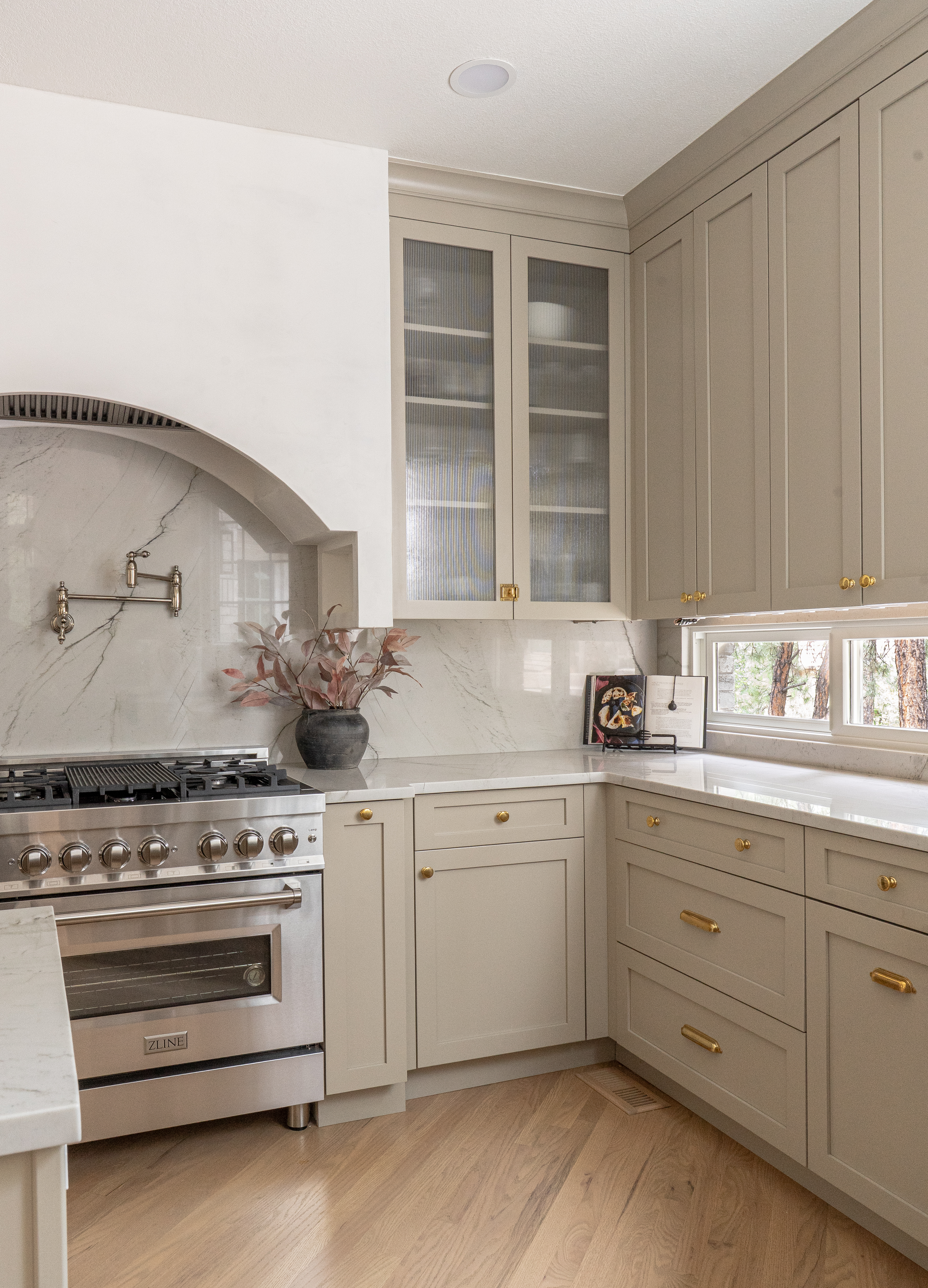 Custom cabinet detail with unlacquered brass knobs and pulls in warm taupe kitchen
