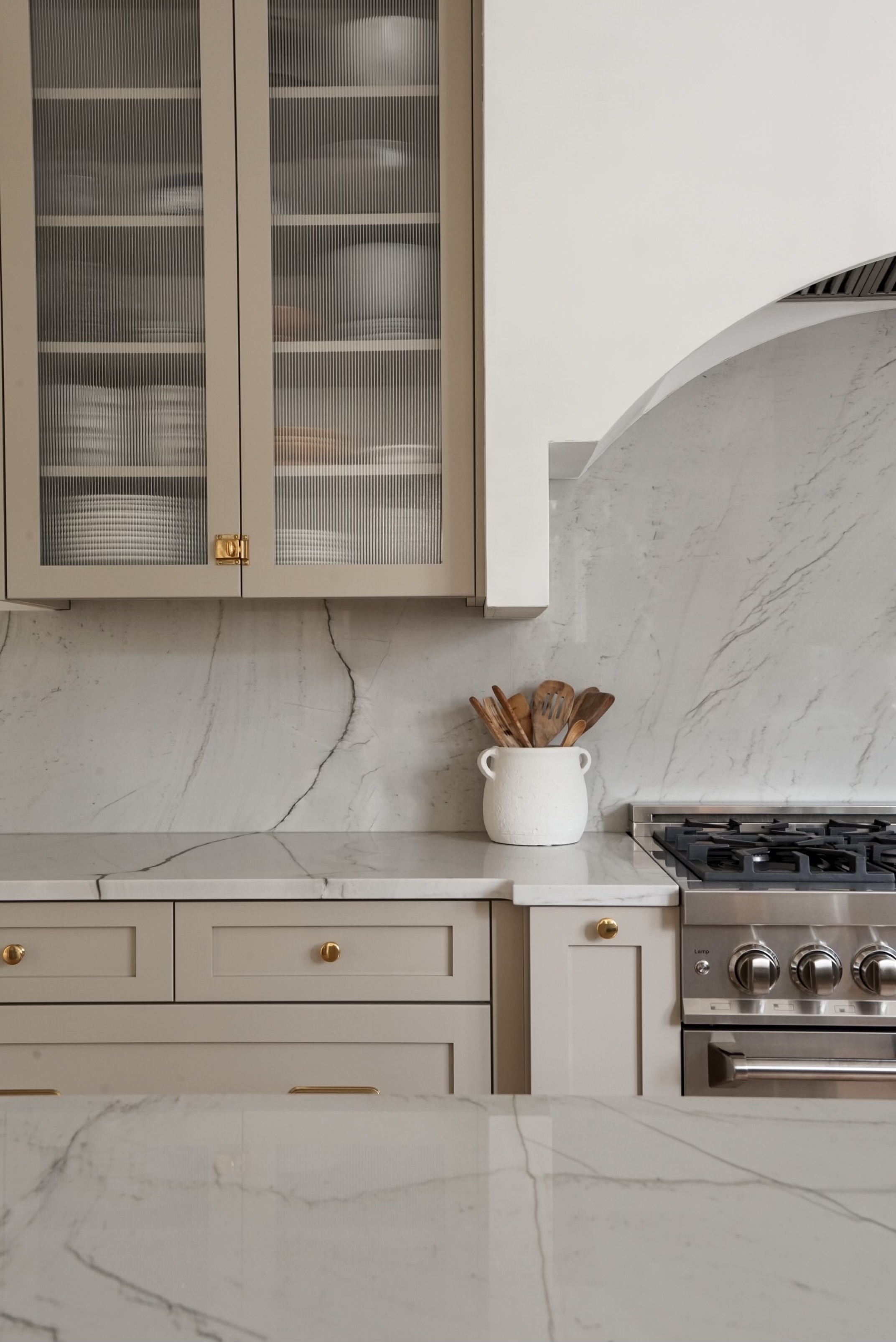 Mixed metal hardware with latches and pulls in warm taupe cabinetry by Halcyon Haus