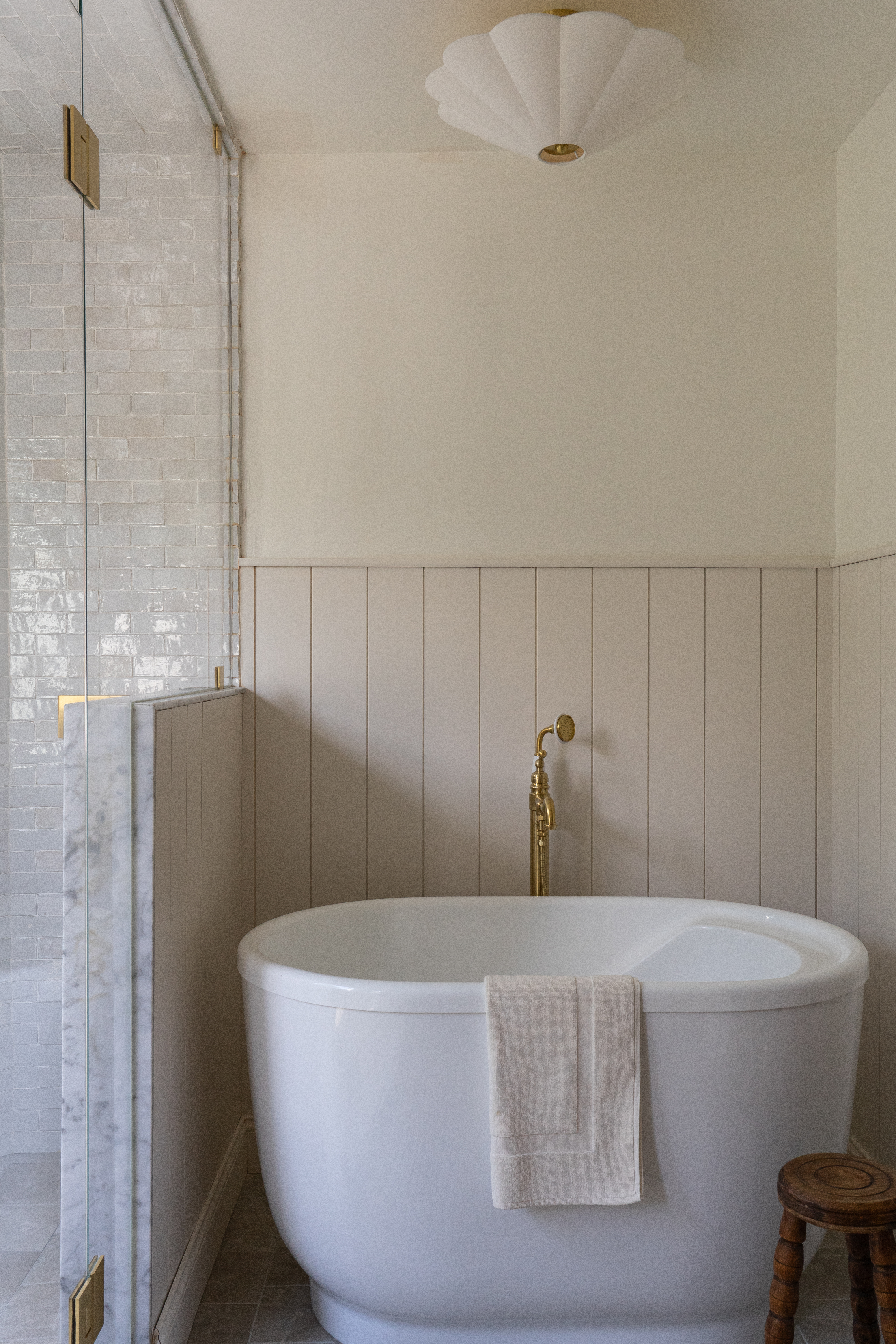 Freestanding tub with painted shiplap paneling and brass tub filler in Castle Pines primary bathroom