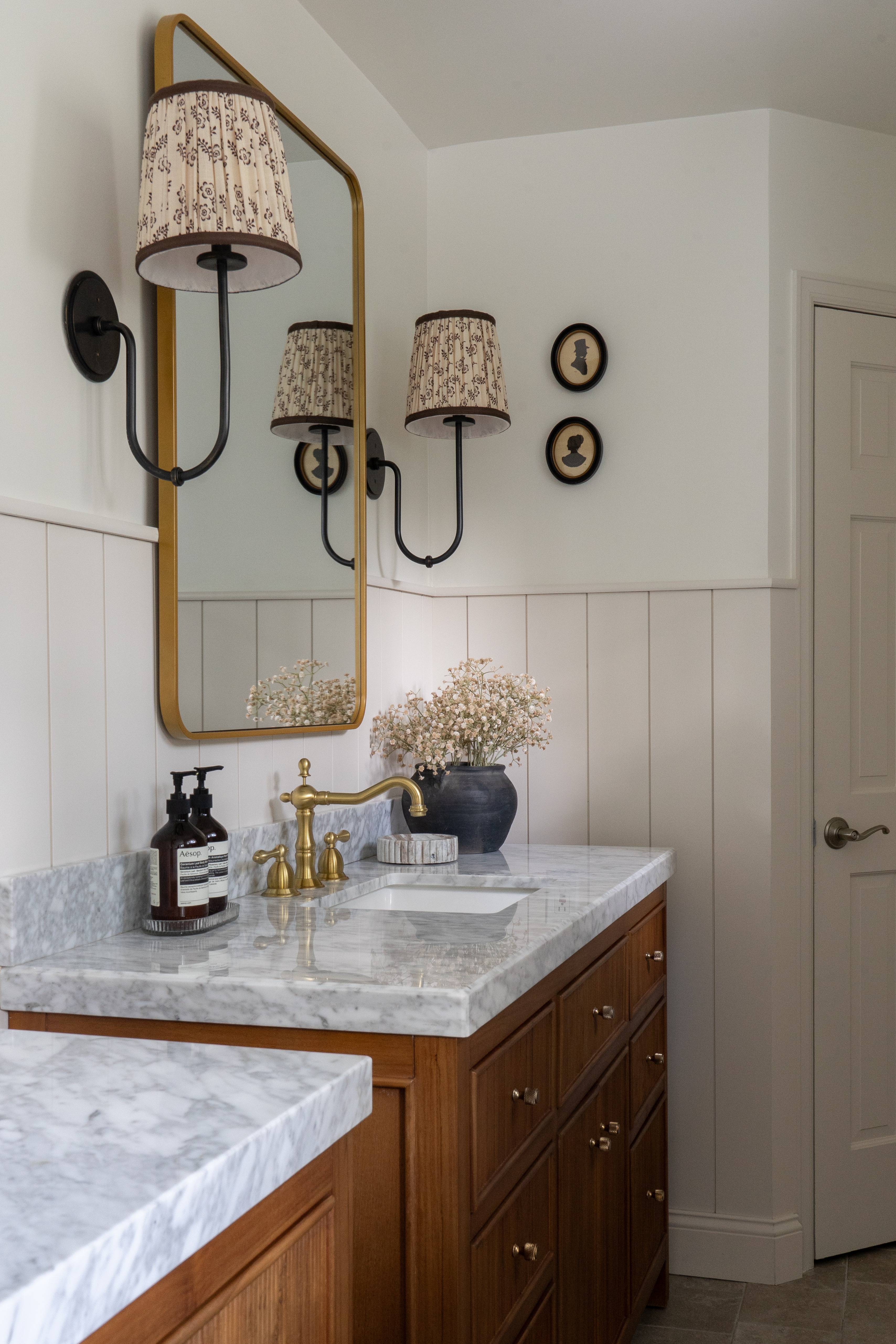 Vanity corner with silhouette portrait art and pleated sconce in Castle Pines primary bathroom
